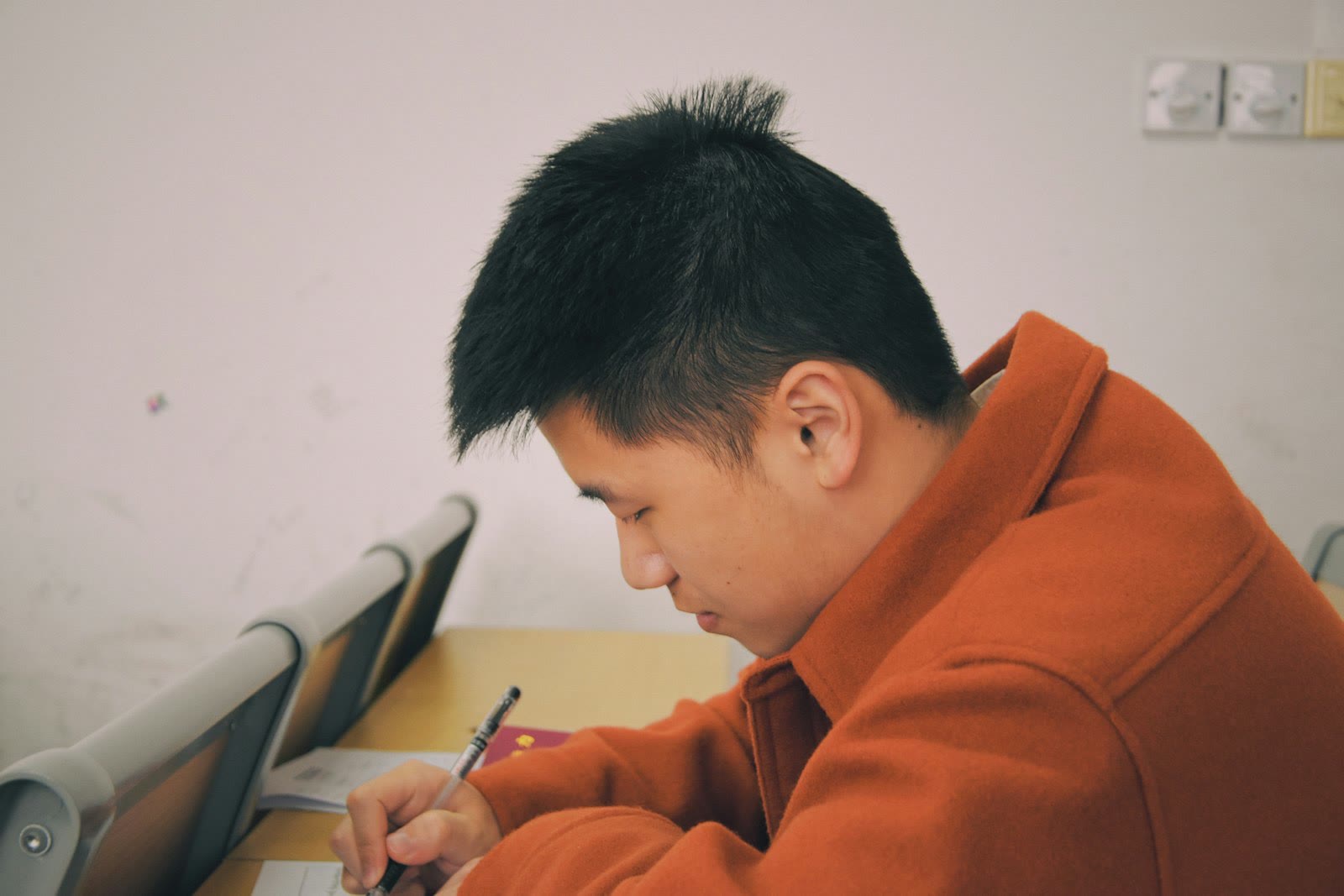man in orange hoodie using smartphone