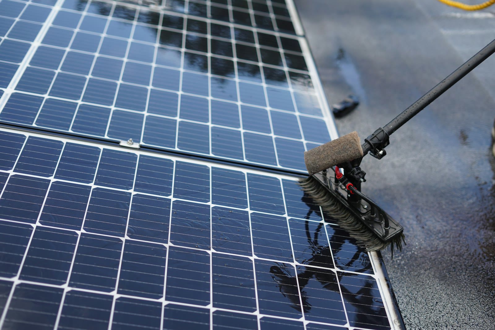 Cleaning solar panels with a long handled brush.
