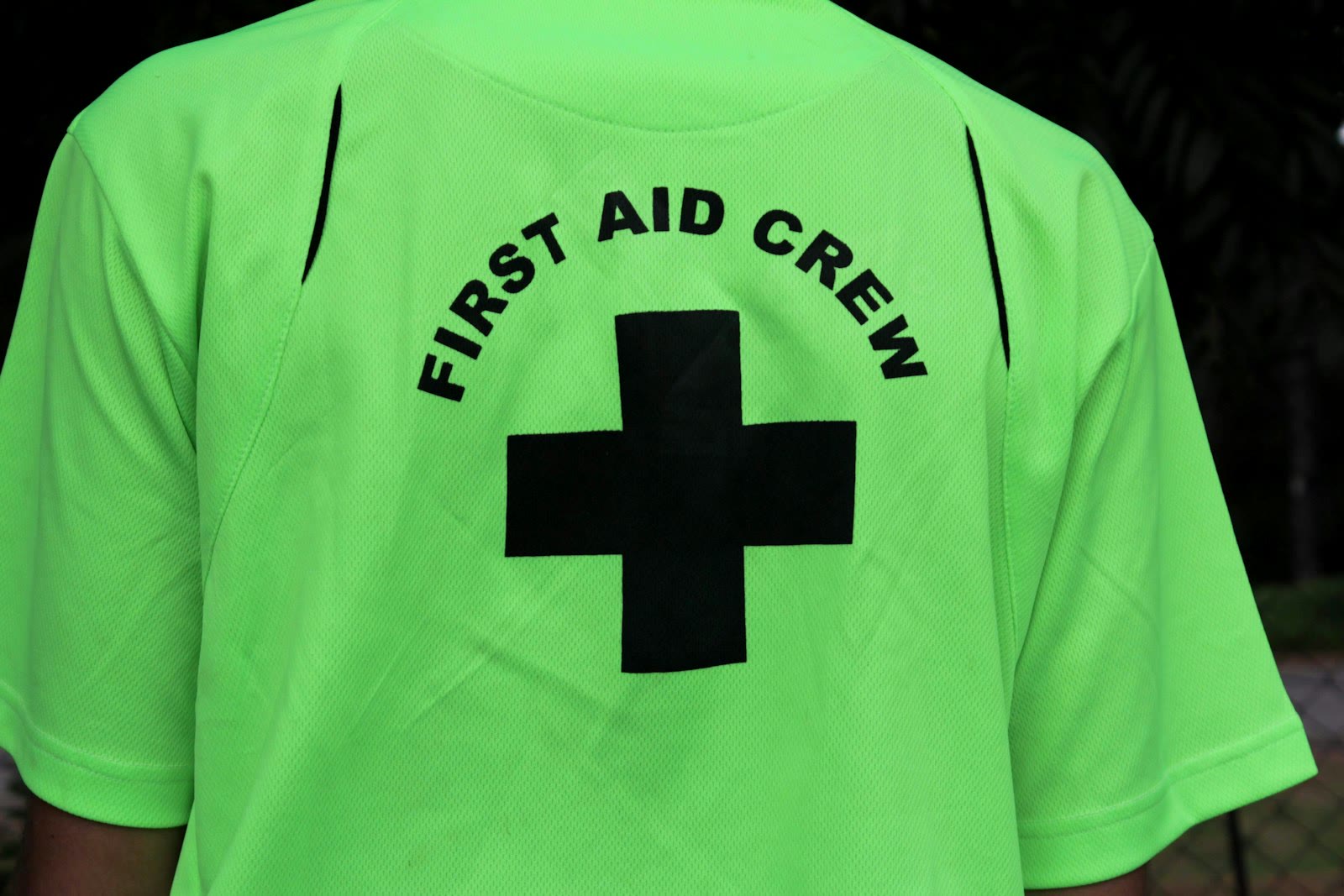 a person wearing a neon green shirt with a black cross on it