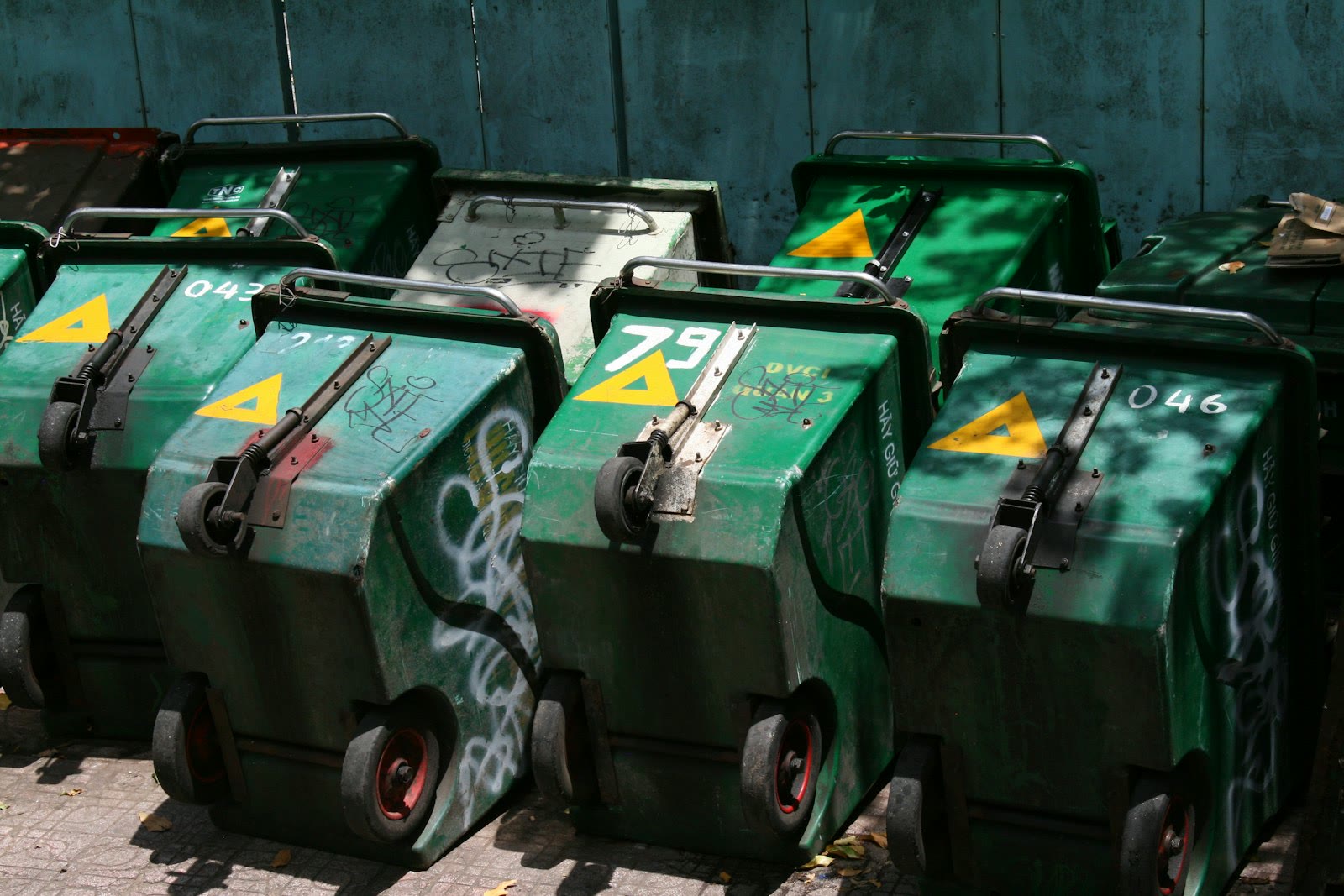 Several green wheeled trash bins are lined up.