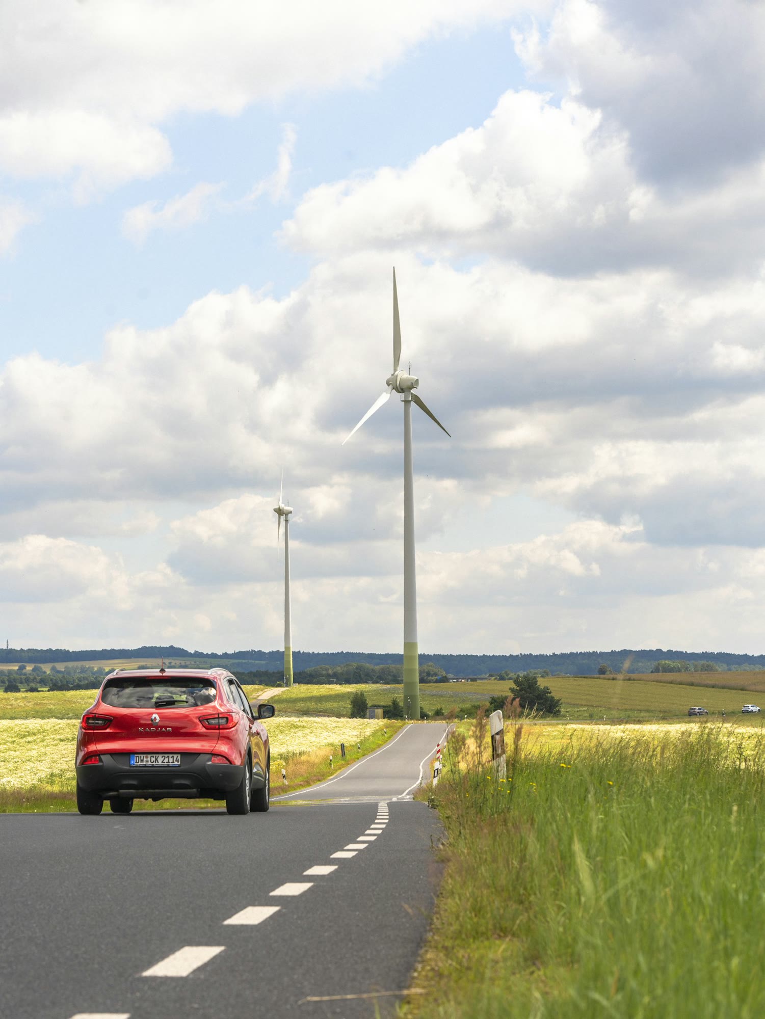 A red car driving down a country road