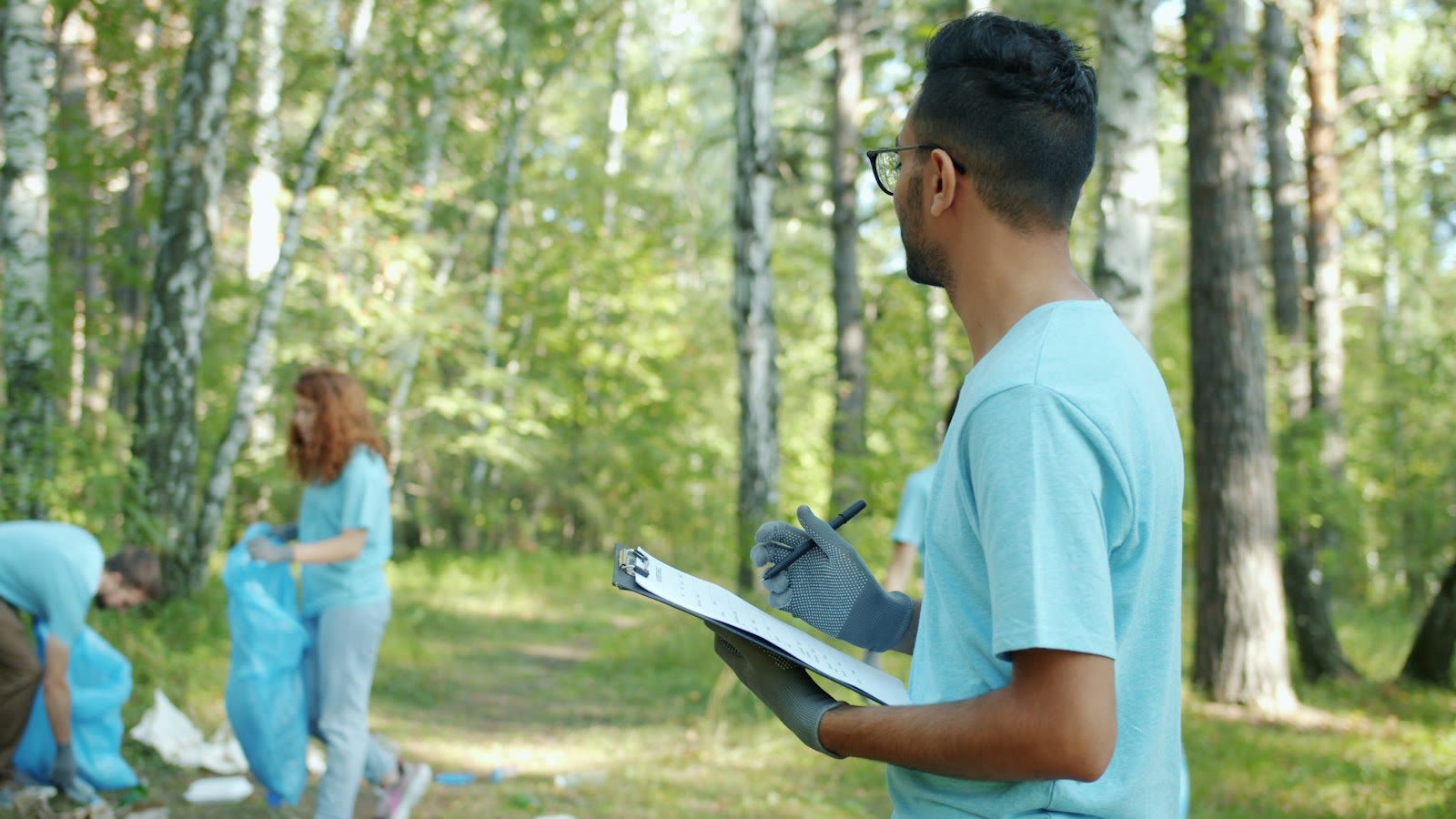 Volunteers cleaning up a forest with trash bags.